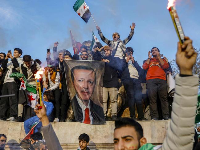 People hold a banner featuring Turkish President Recep Tayyip Erdogan as members of the Syrian community and supporters gather to celebrate the fall of Syrian president Bashar al-Assad in the face of an offensive by Islamist-led rebels, in Istanb's Fatih district on December 8, 2024. Islamist-led rebels toppled Syria's longtime ruler Bashar al-Assad in a lightning offensive that a UN envoy called "a watershed moment" for the nation marred by civil war. (Photo by KEMAL ASLAN / AFP)