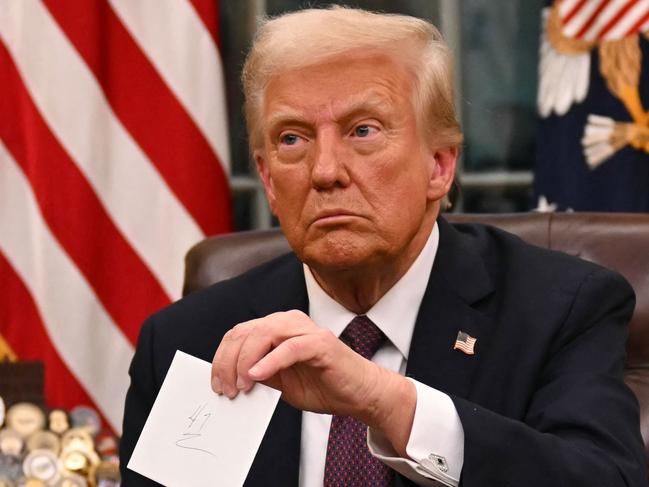 US President Donald Trump holds up outgoing President Joe Biden's letter as he signs executive orders in the Oval Office of the WHite House in Washington, DC, on January 20, 2025. (Photo by Jim WATSON / POOL / AFP) / ALTERNATE CROP