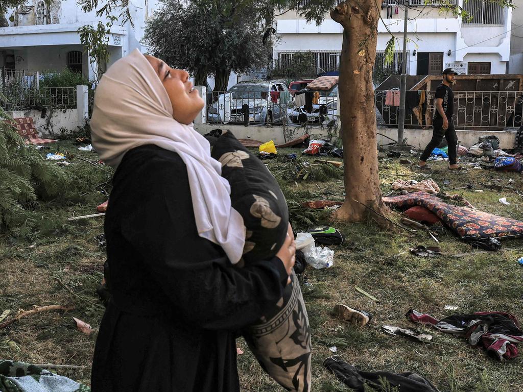 A woman reacts while holding a pillow as she stands amidst debris outside the bombed hospital site. Picture: AFP