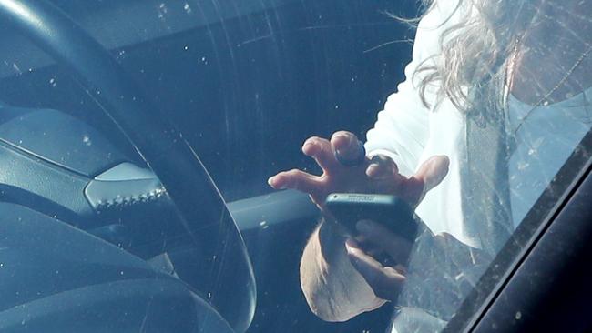 A woman in the driver's seat, using a mobile phone at a set of traffic lights on Warringah Rd, Frenchs Forest. More than 33,000 Sydney drivers have been snapped illegally using their phones in a four-month period. Picture: Damian Shaw