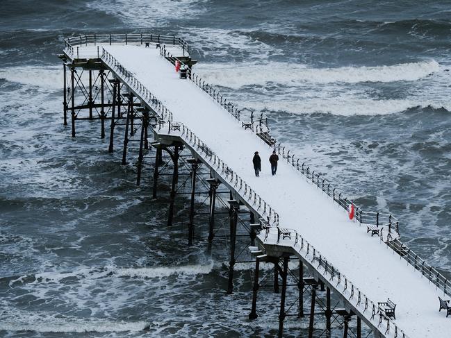 A couple walk along the snow covered pier at the beach on February 27, 2018 in Saltburn-By-The-Sea, England. A cold weather front from Russia brings snow across much of the UK with further snow showers pushing in from the east. The cold weather is set to continue through the week with frequent snow showers in the east of England and along the coast in the south-west. Picture: Getty Images