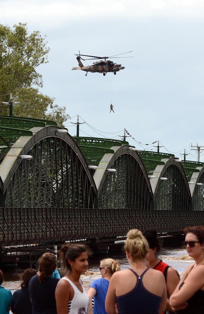 Residents watch an army Blackhawk helicopter performing a rescue from a property affected by the swollen Burnett River on January 28, 2013. At least 1200 Bundaberg properties flooded at the time.