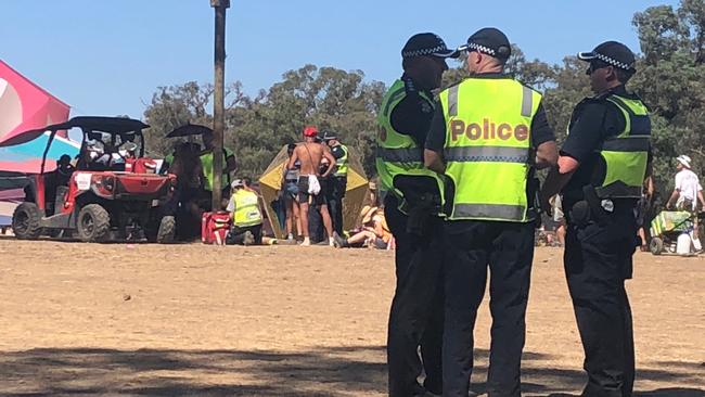 Police stand by as medics work on a man at Rainbow Serpent Festival. 