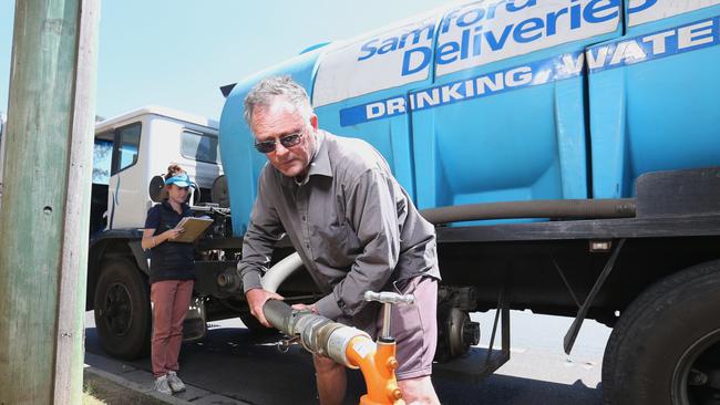 Michael Hocken from Samford Water Deliveries, filling up their truck before making another delivery. Picture: AAP/Steve Pohlner.