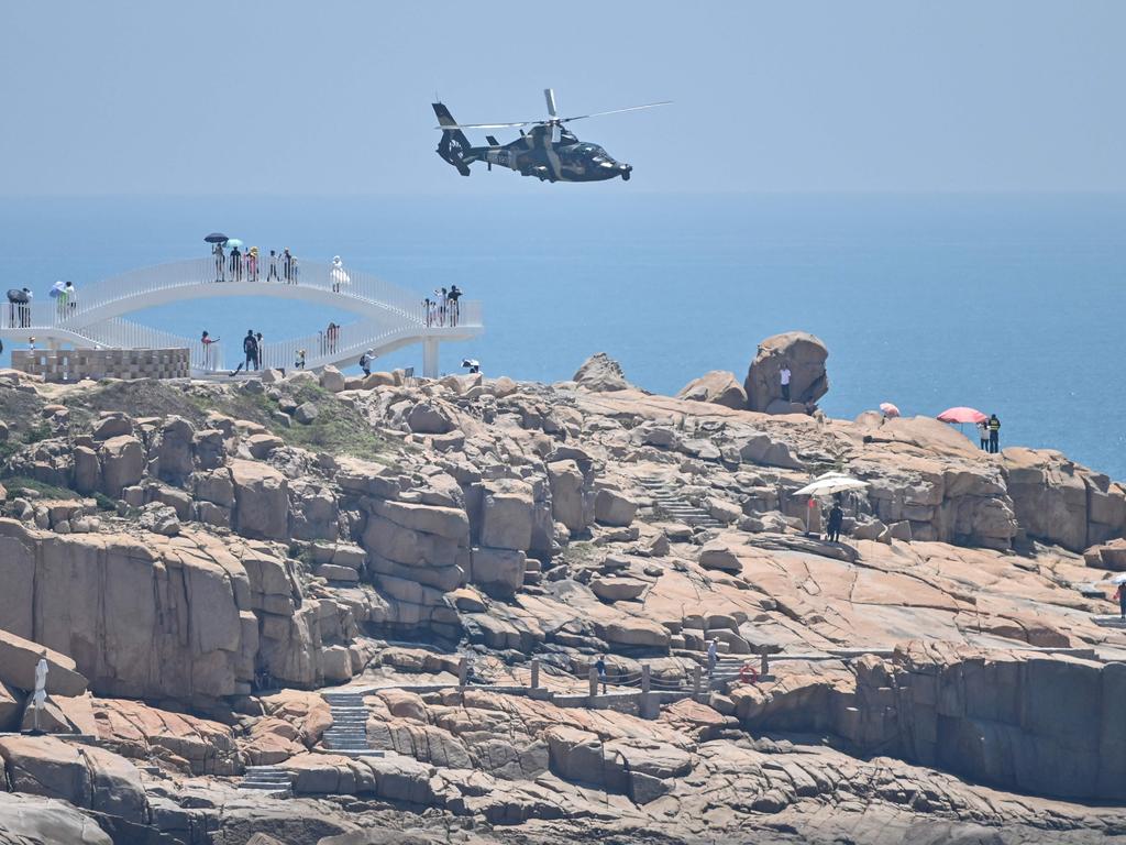 Tourists look on as a Chinese military helicopter flies past Pingtan island, one of mainland China's closest point from Taiwan, in Fujian province on August 4. Picture: Hector Retamal/AFP