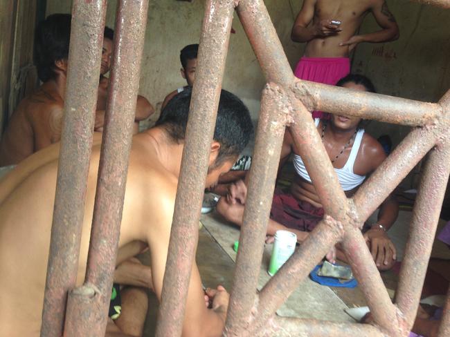 In this Saturday, Nov. 22, 2014 photo, Thai and Burmese fishing boat workers sit inside a cell at the compound of a fishing company in Benjina, Indonesia. The imprisoned men were considered slaves who might run away. They said they lived on a few bites of rice and curry a day in a space barely big enough to lie down, stuck until the next trawler forces them back to sea. (AP Photo/Dita Alangkara)