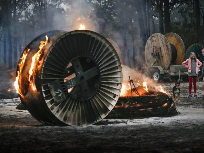 East Gippsland fires Mallacoota township. Destroyed homes in the township. Jessica Tregellas aged 12 and her sister Emily aged 15 walk their dog amongst burning NBN cable rolls.    Picture: David Caird