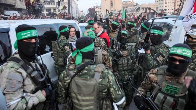 Members of the International Committee of the Red Cross (ICRC) speak with Hamas fighters as the handover begins. Picture: AFP.