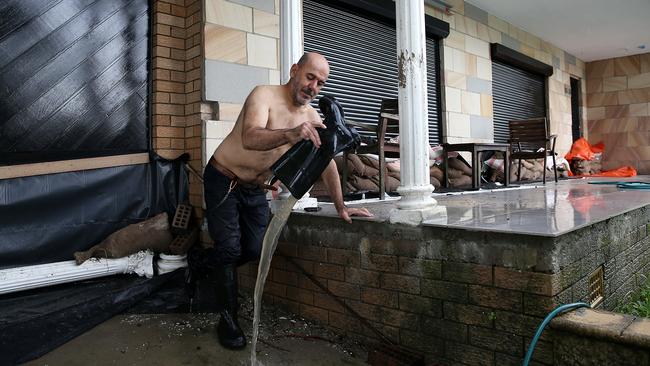 Tom Geb empties his gumboot at his son’s house in Moorebank, near the Georges River southwest Sydney, on Tuesday. Picture: Jane Dempster