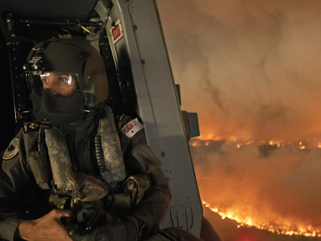 Royal Australian Navy Aircrewman Leading Seaman Ben Nixon of 808 Squadron, assesses the Tianjara Fire in the Moreton and Jerrawangala National Parks out of an MRH90 Taipan Military Support Helicopter. Picture: ADF