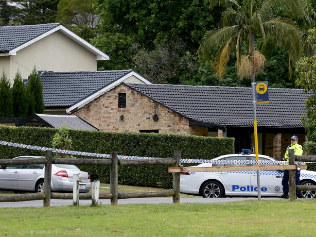 A police officer stands guard out the front of the house. Picture: Jonathan Ng