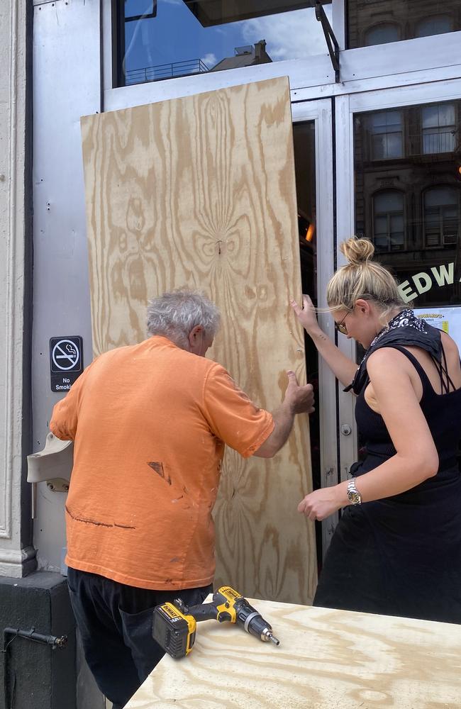 Brisbane model Georgina Burke helping her neighbour board their business after riots. Pic: Supplied