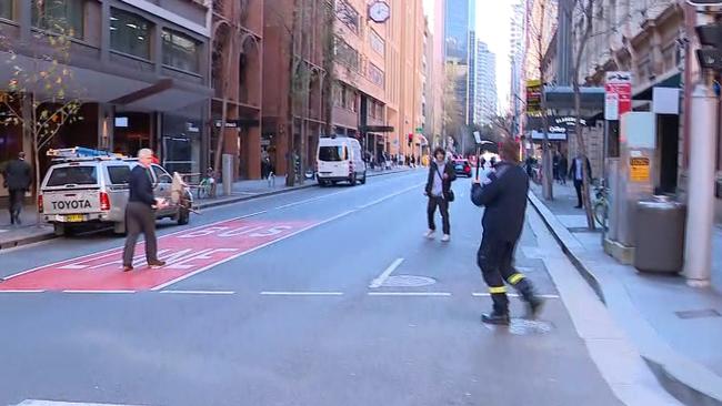 A firey holding up a fireman’s axe and the same city worker holding a chair approach Ney forcing him to back down the street. Picture: Seven News