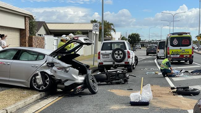 A silver Kia sedan crashed into the brick fence at the front of a home, next to where a black motorcycle laid crushed on the road. Photo: Kathleen Skene