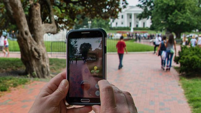 A woman holds up her cell phone as she plays the Pokemon Go game in Lafayette Park in front of the White House in Washington, DC. Picture: Jim Watson