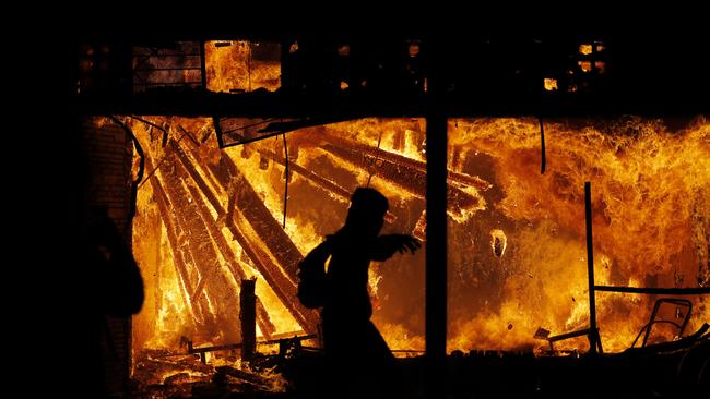 A protester runs in front of the burning 3rd Precinct building of the Minneapolis Police Department, as riots broke out again over the death of George Floyd, a black man who died in police custody. Picture: AP