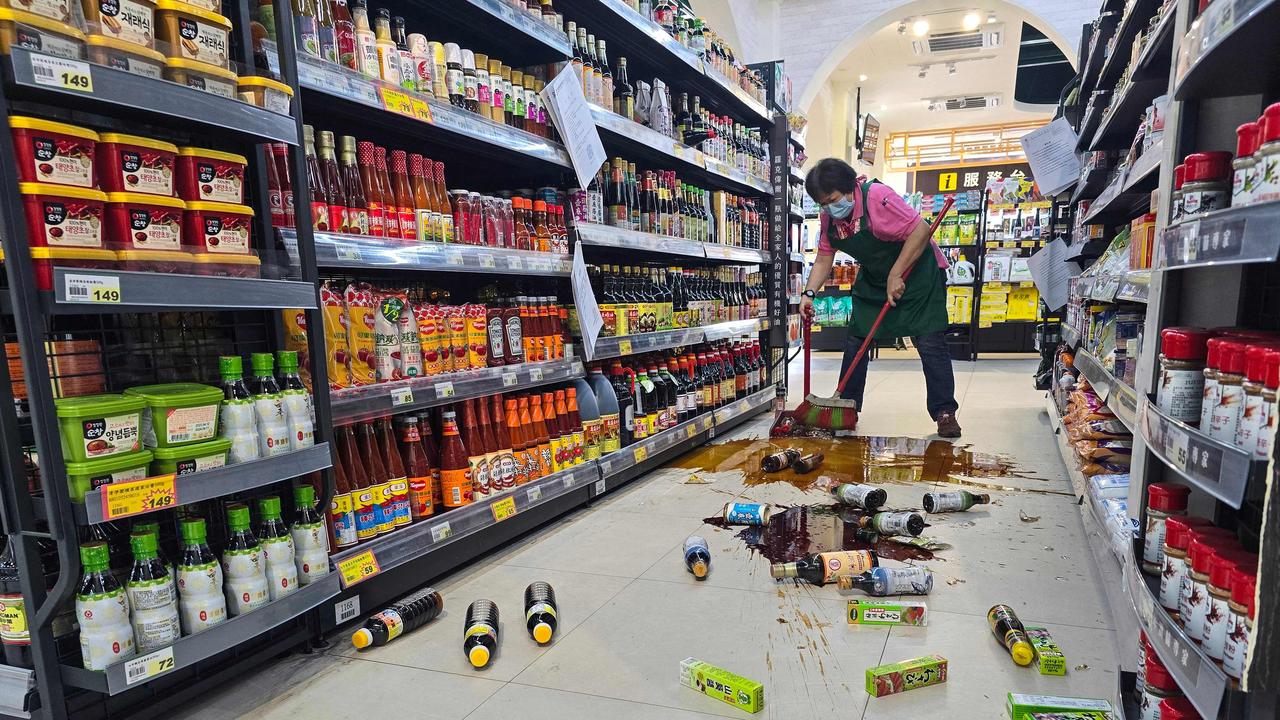 A supermarket worker cleans up after the tremors knocked items off the shelves. Picture: CNA/AFP