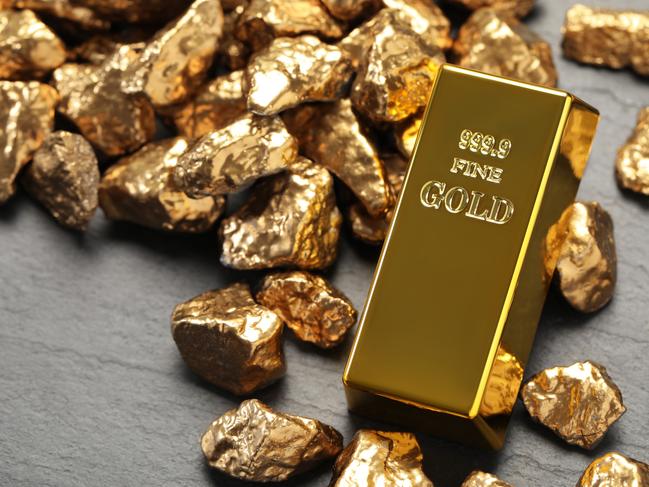 Gold ingot and nuggets on grey table, closeup