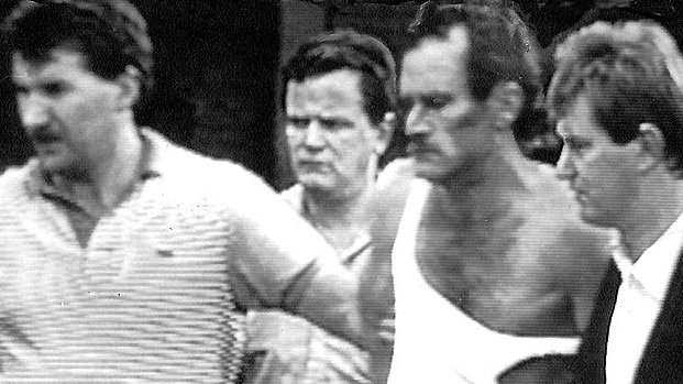 Russell Cox (singlet) is led away after his capture with fellow escapee Ray Denning at Melbourne's Doncaster Shopping Centre in 1988.