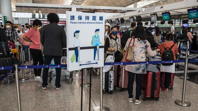 People wait in a queue to check-in for their flight. Hong Kong is lifting flight bans on nine countries after ending its “Covid zero” hopes. Picture: AFP.