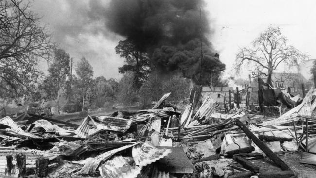 Smoke billows from a building as the ruins of a barn lay in the foreground in the wake of the devastating Ash Wednesday bushfires of 1983. Photo: Barry Hartley / The Advertiser.