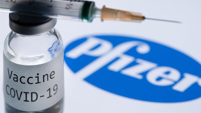 (FILES) This file photo taken on November 23, 2020 shows a syringe and a bottle reading "Covid-19 Vaccine" next to the Pfizer company logo. - Pfizer reported another quarter of huge revenues growth because of the Covid-19 vaccine on May 3, 2022, but lowered its full-year profit forecast due in part to shifts in foreign exchange. (Photo by JOEL SAGET / AFP)