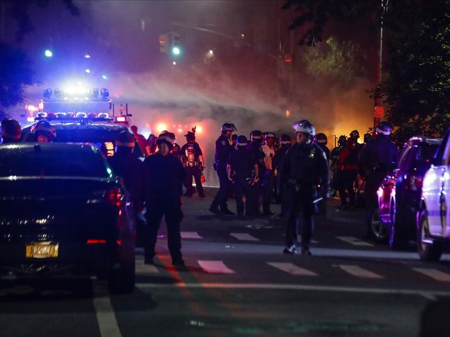 Fire work on a New York police vehicle that was set on fire as Police Officers control the crowd near Fort Greene Park after protesters rallied at the Barclays Center. Picture: AP