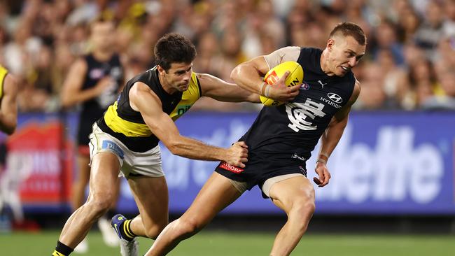 MELBOURNE. 18/03/2022. AFL. Round 1. Carlton vs Richmond at the MCG. Patrick Cripps of the Blues breaks the tackle of Richmonds Trent Cotchin during the 3rd qtr. . Photo by Michael Klein