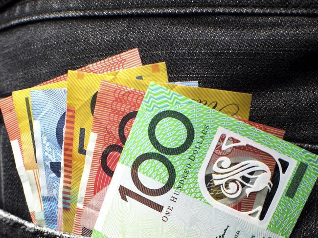 Australian money including 100, 50, 5, 10 and 20 dollar notes, in back pocket of a man's black charcoal jeans pocket. Vertical.