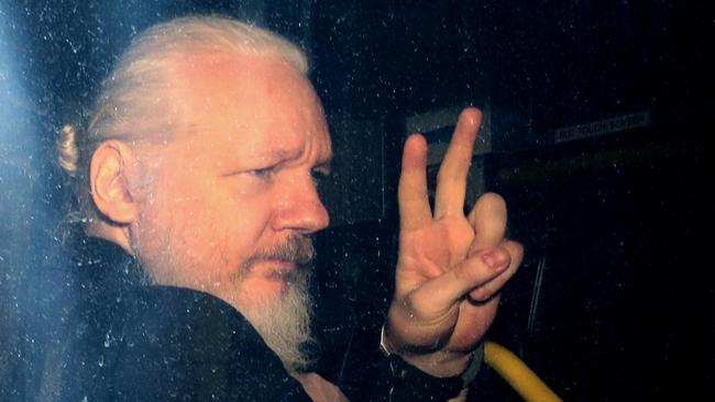 Julian Assange gestures to the media from a police vehicle on his arrival at Westminster Magistrates Court. Picture: Getty