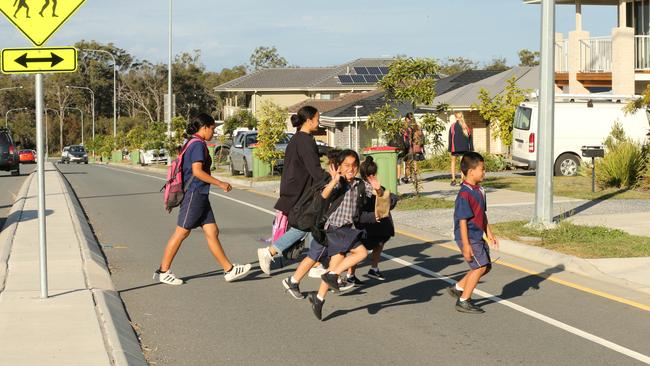 Students and parents of Pimpama state school crossing the road in front of their school. Picture: Mike Batterham.