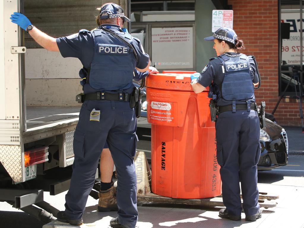 Police are seen remove hazardous material from the apartment following the murder. Picture: Jono Searle