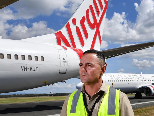 Airside operations team leader Chris McCullen is seen with grounded Virgin Australia aircraft at Brisbane Airport in Brisbane, Tuesday, April 7, 2020. Brisbane Airport Corporation (BAC) is working with airlines by accommodating up to 100 grounded aircraft free of charge in response to government-mandated travel restrictions that have grounded a significant proportion of Australia's airline fleet because of the Coronavirus (COVID-19). (AAP Image/Darren England) NO ARCHIVING