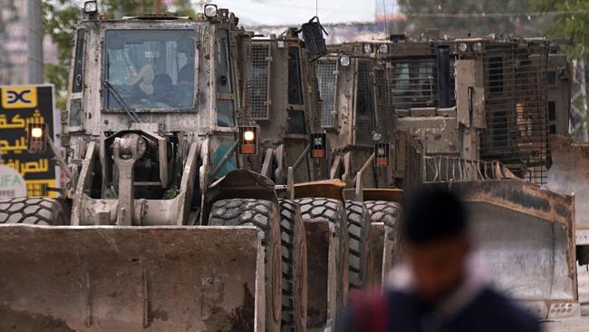 A Palestinian man walks past the Israeli army vehicles in a street during a military raid in Jenin described as a "counter-terrorism" operation. Picture: AFP