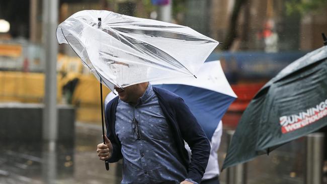 A commuter battles with his umbrella amid heavy rain and wind at Circular Quay this morning. Picture: Dylan Robinson