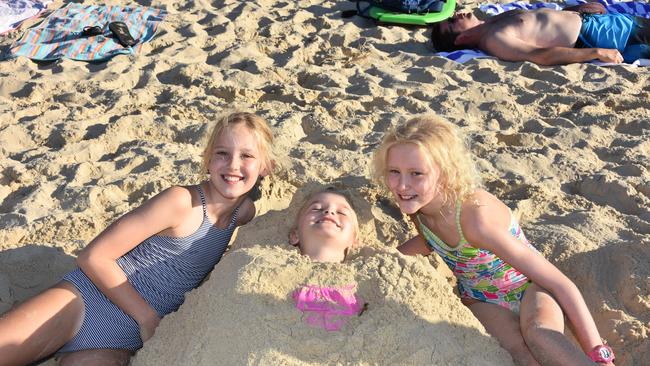 Easter holidays Noosa Main Beach: Emily and Gracie turned young Ella into a sand mermaid during their holiday from Mackay.