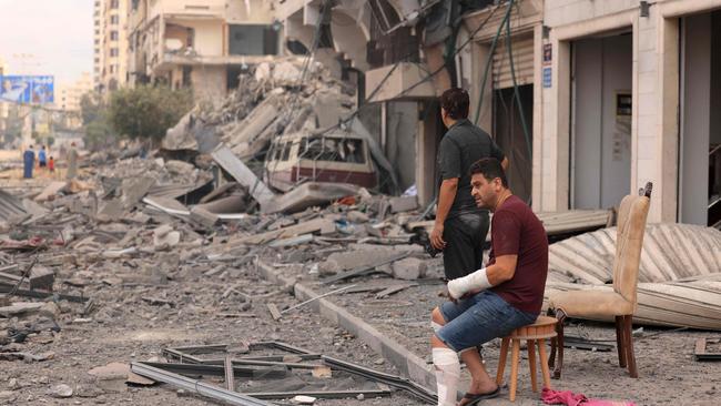 Palestinian men look at the destruction outside a damaged apartment building following Israeli airstrikes on Gaza City on October 10, 2023. Picture: Mahmud Hams/AFP