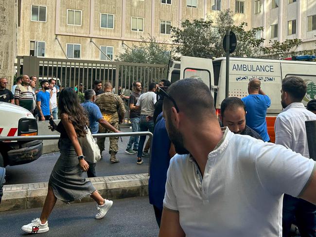 People react near an ambulance as the wounded are brought to a hospital in Beirut. Picture: AFP