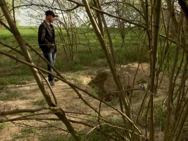 Mykola Kulichenko at an unmarked grave he says he was buried alive in. Picture: CNN