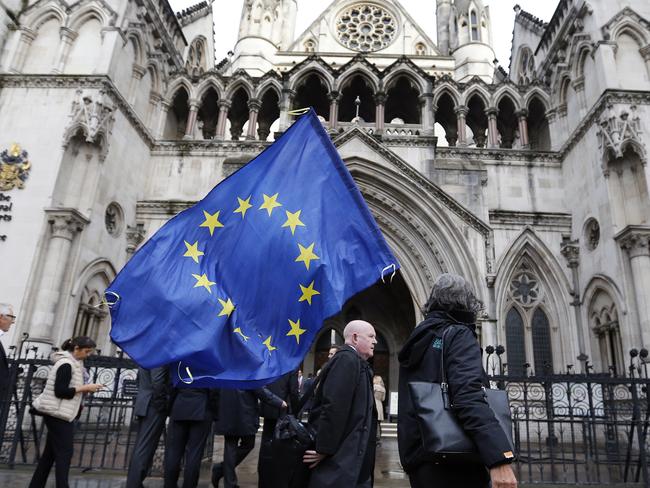 A Pro-EU membership supporter walks with a EU flag outside the High Court, on the second day of the lawsuit of Gina Miller, a founder of investment management group SCM Private in London, Monday, Oct. 17, 2016. Rival protesters have gathered outside the High Court in London, where lawyers are battling over whether the government has the power to trigger Britain's exit from the European Union without approval from Parliament. (AP Photo/Frank Augstein)