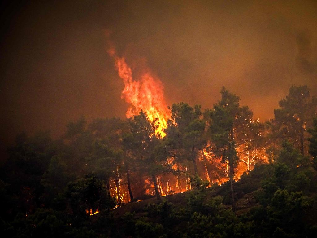 Coastguards lead more than 20 boats in an emergency evacuation to rescue people from the island of Rhodes where fire has been raging out of control for five days. Picture: AFP