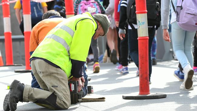 Workers screw in steel screws which are being added to the Southbank pedestrian bridge to ease the noise of the planks created when people walk on the bridge.Picture:Ian Currie