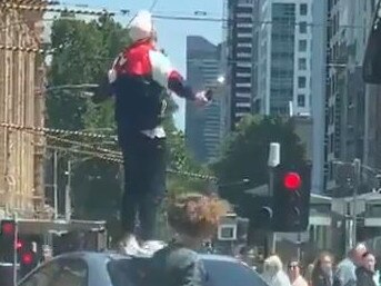 A man speaks from atop a car in Flinders St, Melbourne.