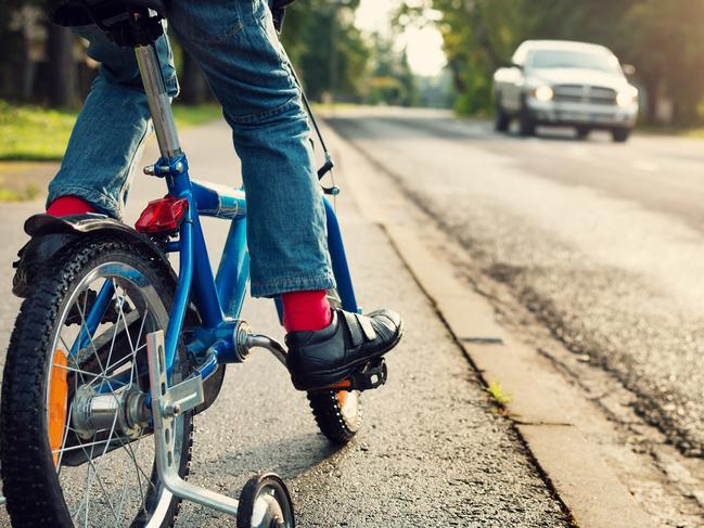 A boy on bike and a car on the road