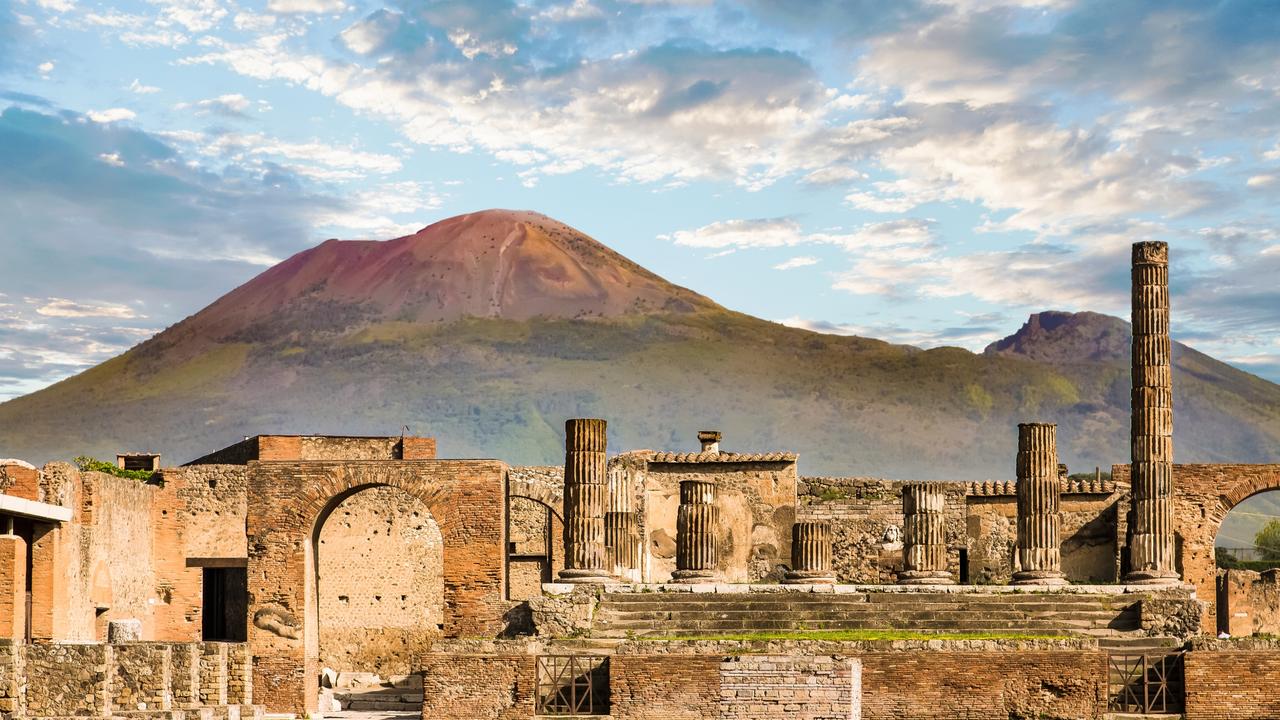 Mount Vesuvius can be seen in the background behind the ancient ruins of Pompeii.