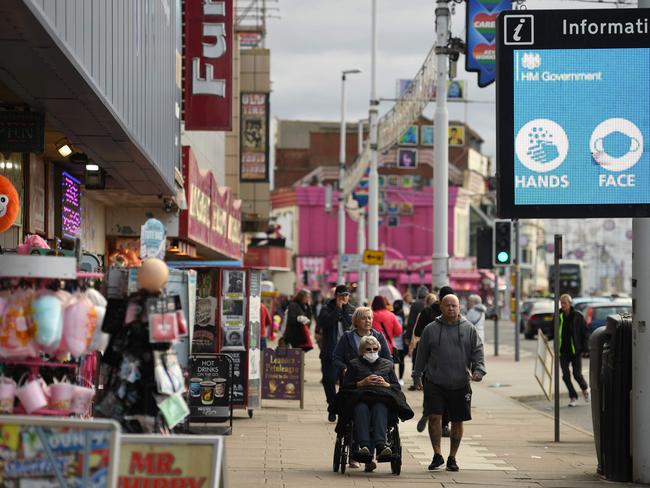 Shoppers wear face-masks stroll past shops in Blackpool, Lancashire. Britain is facing another coronavirus surge. Picture: AFP