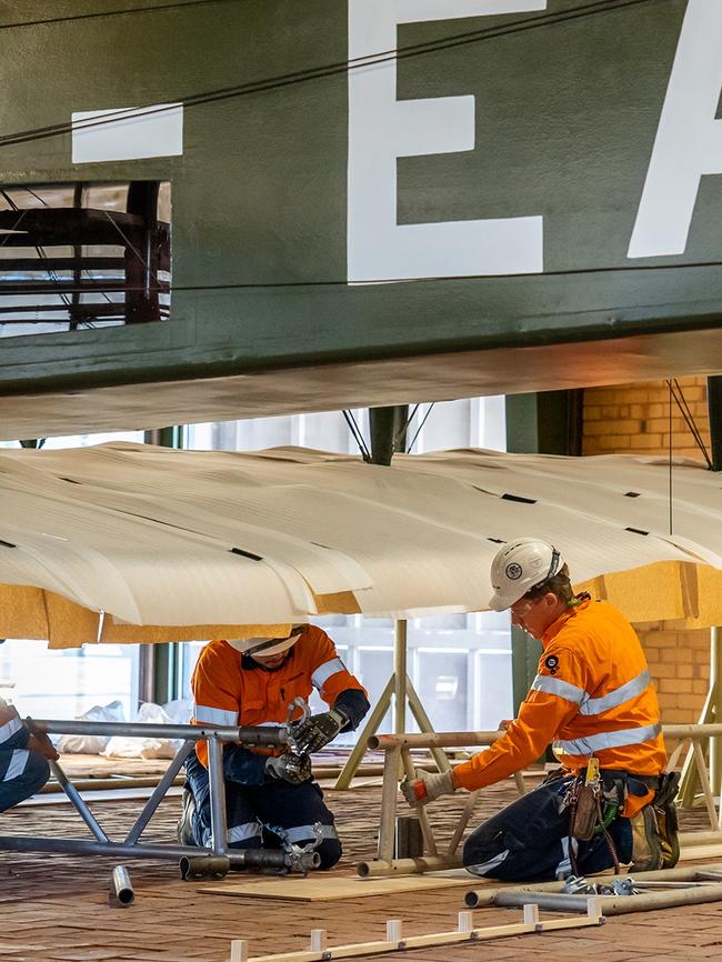 Members of the Vickers Vimy project team dismantling the plane at Adelaide Airport. Picture Lev Luo