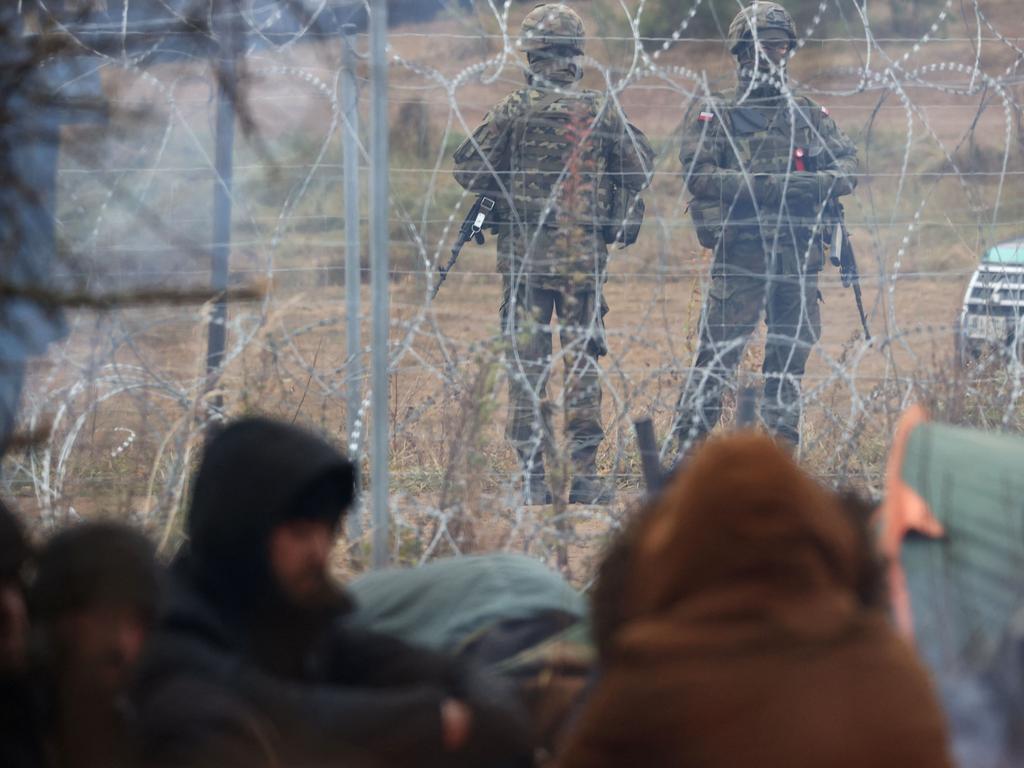 Polish troops watch migrants camping on the Belarusian side. Picture: Ramil Nasibulin/BELTA/AFP