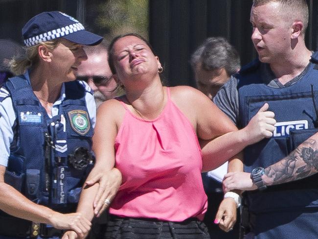 Daily Telegraph - Pictured: A visibly upset woman is led from the scene - A man was shot today in at an industrial complex in Ingleburn NSW Australia. A body can be seen covered in a white sheet on the ground outside of a premises near to the intersection of Moorlands Road and Stennett Road. NSW Police, Ambulance NSW and Tactical Police were in attendance.