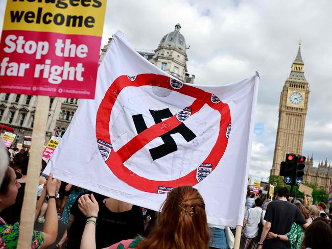 People hold anti-fascist banners, featuring a crossed-out Swastika as they take part in a "Stop the Far-right" march to Westminster, on a National Day of Protest, in London on August 10, 2024. Brexit activist Nigel Farage, whose anti-immigration Reform UK party won 14 percent of the vote on the July 4 general election, has suggested the recent rioting stems from legitimate grievances about immigration, rather than simply far-right thuggery, and warned worse could be seen on the streets. (Photo by BENJAMIN CREMEL / AFP)